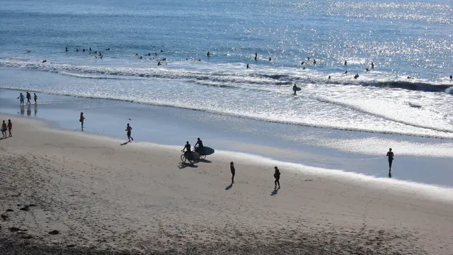 Surfers heading into the water at Moonlight Beach